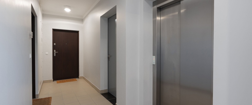 Clean, well-lit apartment hallway with a secure front door and elevator, illustrating the importance of spring break safety when choosing rental accommodations.
