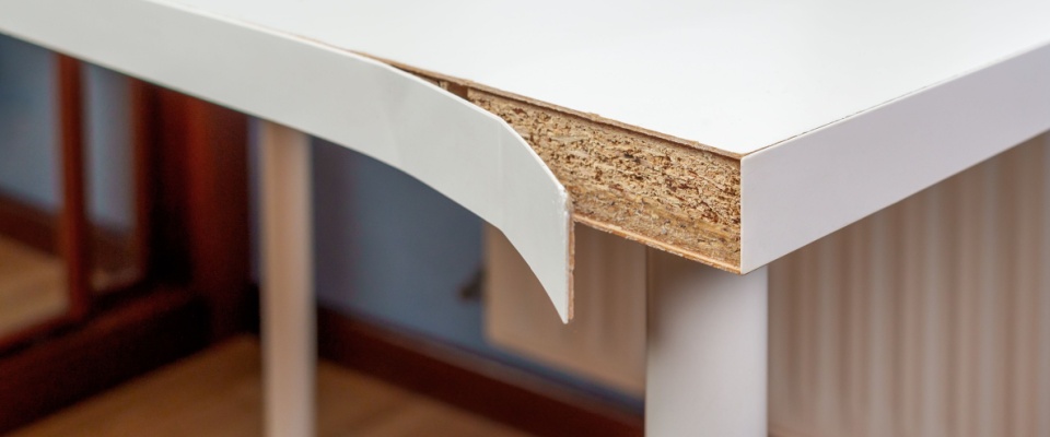 Close-up of a damaged wooden table with a chipped corner, representing personal belongings renters insurance covers property damage for.