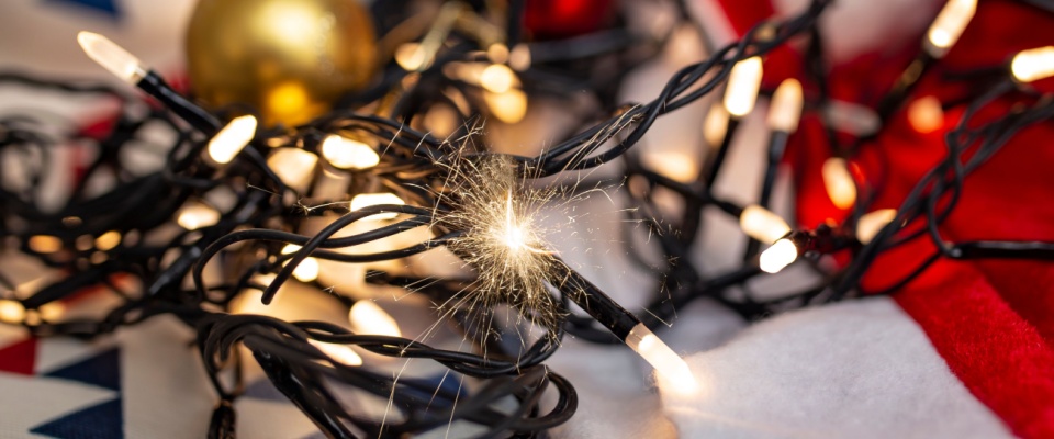 Close-up of faulty holiday string lights sparking, emphasizing key holiday safety tips for preventing electrical fires.