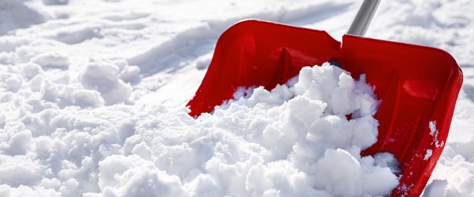 Red snow shovel clearing heavy snowfall, illustrating essential snow shoveling safety tips to prevent strain and winter injuries.