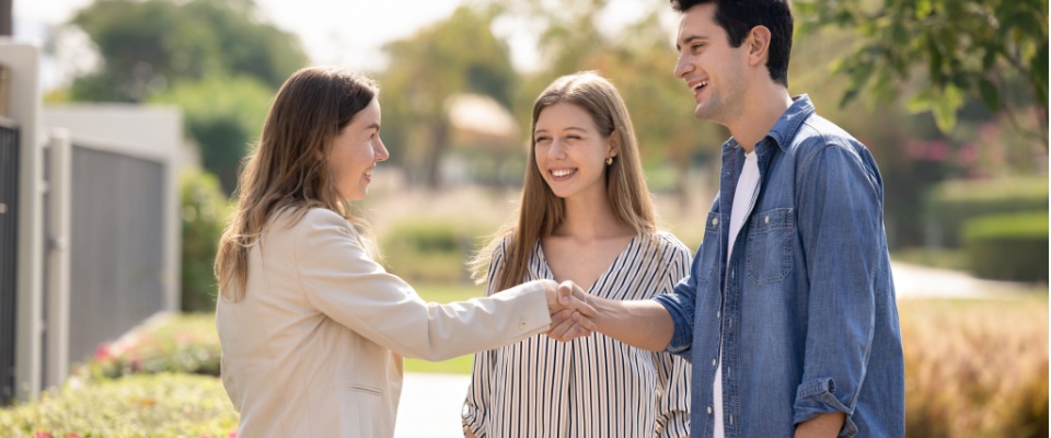 Three people meeting outdoors and shaking hands, illustrating one of the ways in which you can protect yourself against rental scams.