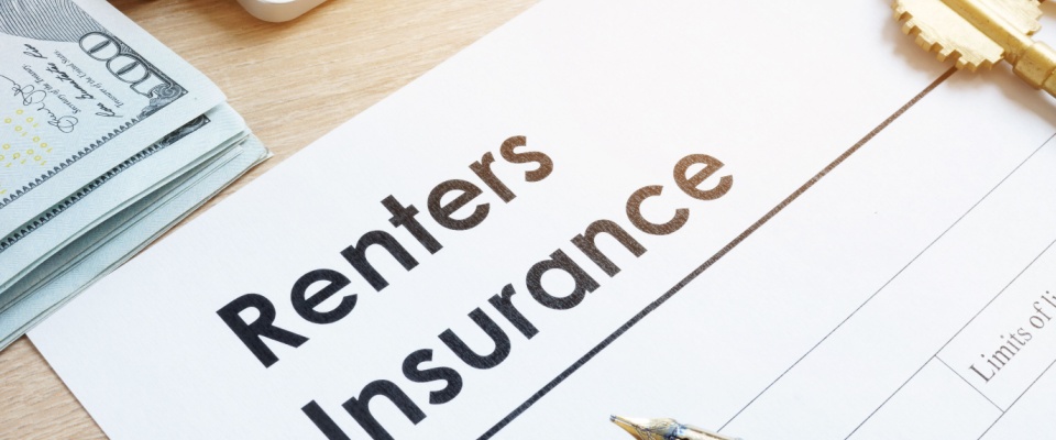 Close-up of a renters insurance policy document on a desk with a stack of hundred dollar bills, a pen, and a key, to be reviewed before deciding to cancel renters insurance.