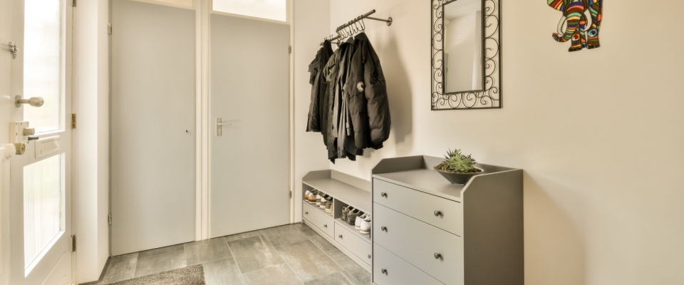 Clean and organized entryway with coats hung neatly and shoes stored properly, illustrating the first steps of a holiday cleaning checklist.