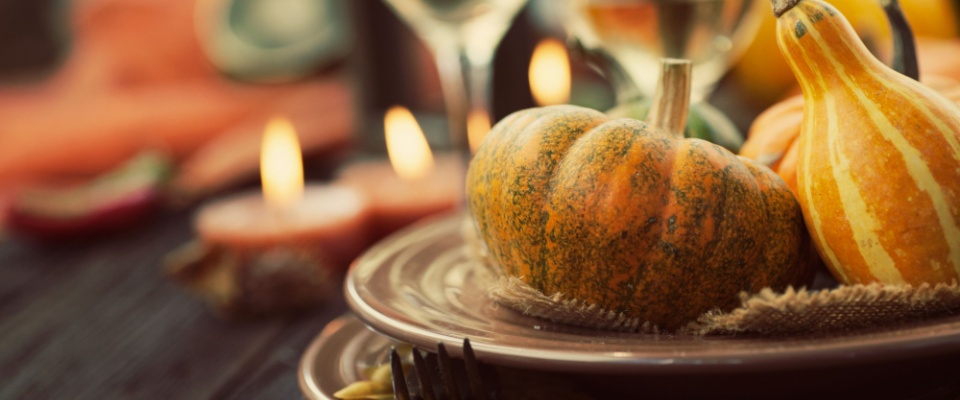 Autumn-themed dinner table setting with small pumpkins, gourds, candles, and rustic plates, offering a festive fall decor idea for hosting seasonal gatherings.