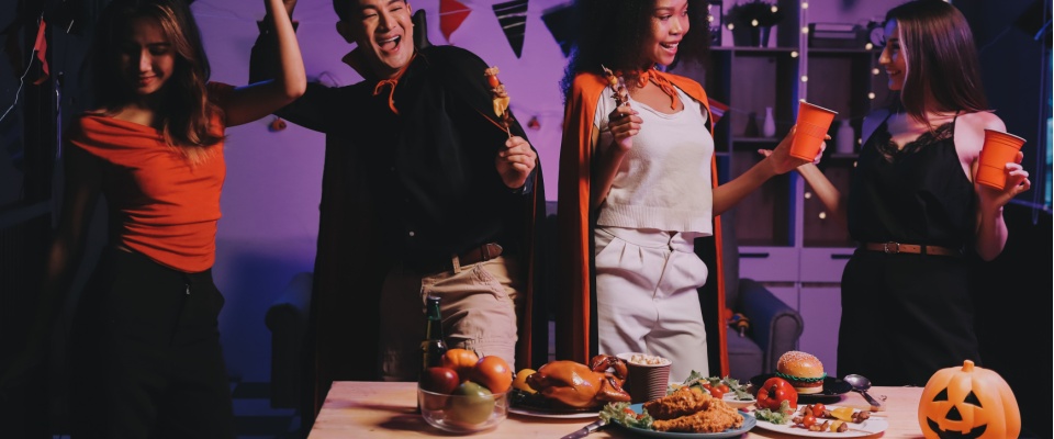 Friends dressed in costumes enjoying a Halloween party with decorations and food, emphasizing responsible fun and Halloween safety.