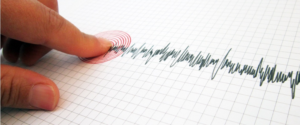 A close-up of a finger pointing at a seismograph spike on graph paper, visually representing seismic activity and highlighting the importance of earthquake coverage with renters insurance.