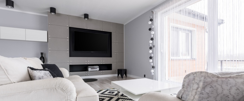 A bright, modern living room with large windows, a stylish sofa, and home electronics highlights the value of protecting personal belongings and assessing whether you need earthquake coverage to your renters insurance policy.