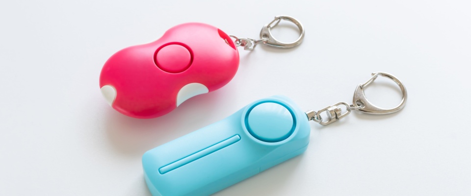 Two handheld personal alarm keychains in bright colors, showing portable safety gadgets designed to help alert others in emergencies.