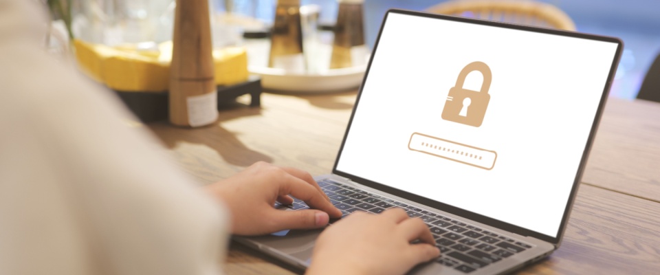 Person typing on a laptop displaying a password and lock icon on the screen, illustrating work-from-home safety best practices for cybersecurity and protecting sensitive information in a home office environment.