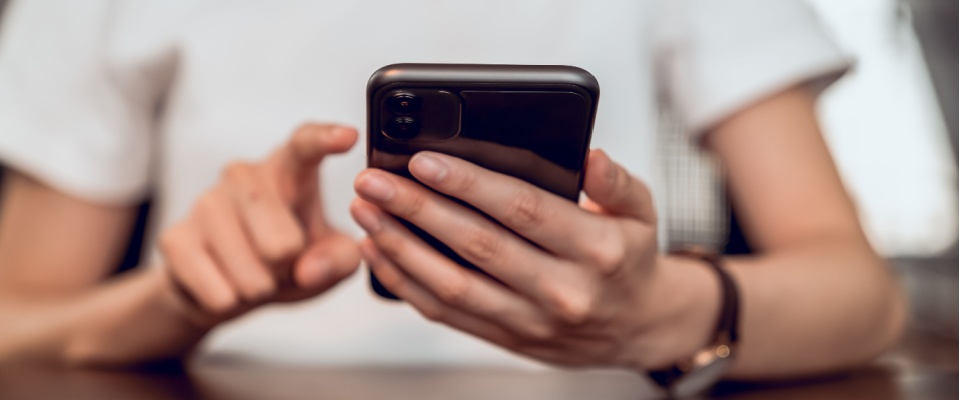 Person using a smartphone to file a renters insurance claim during Halloween for personal property damage.
