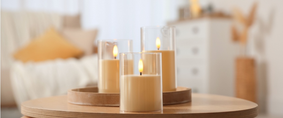 Lit candles in glass holders on a table, showing a key Thanksgiving safety tip about practicing caution with open flames during celebrations.