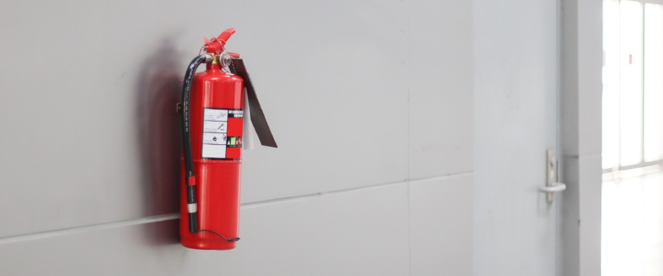 Red fire extinguisher mounted on a wall, representing important Thanksgiving safety tips for preventing kitchen and holiday fires.