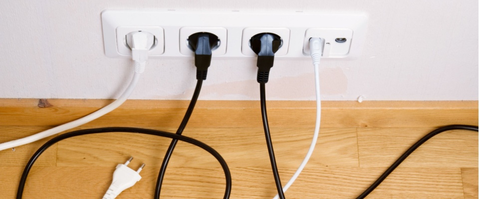 Overloaded electrical outlet with several plugs connected, highlighting safety considerations when hosting a New Year’s Eve party.