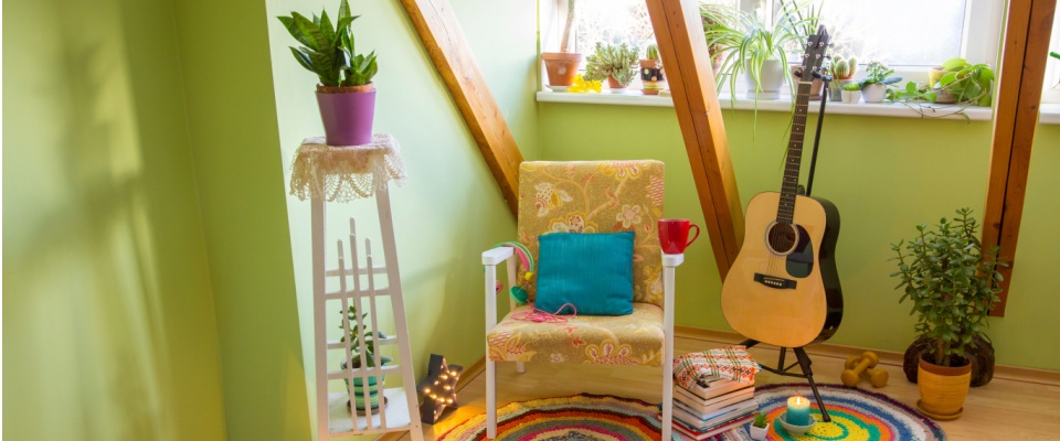 Vibrant room with plants, colorful furniture, books, and personal decor, illustrating interior design trends inspired by maximalism and self-expression.