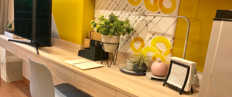 Sleek home workspace with integrated desk, shelving, and decor, reflecting interior design trends centered on multifunctional furniture and smart layouts.