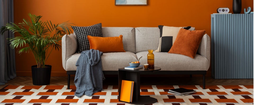 Modern living room with bold colors, layered textiles, and geometric rugs, showcasing current interior design trends focused on patterns and warmth.