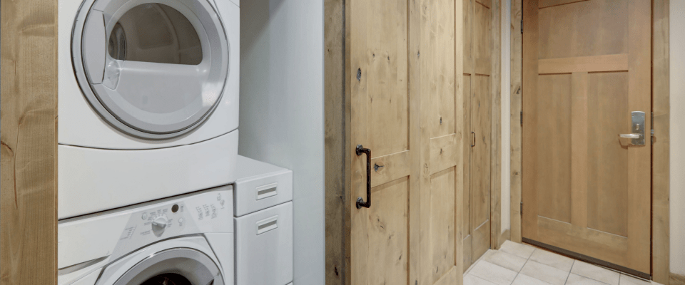 Compact laundry area with stacked washer and dryer and rustic wooden sliding doors, impacting the average electricity bill.