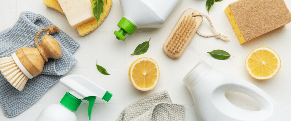 Eco-friendly spring cleaning items for the kitchen, featuring lemons, wooden brushes, and other natural cleaning supplies.