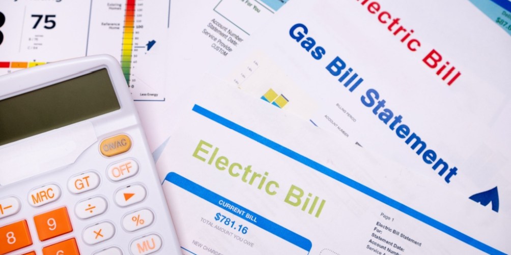 Calculator on top of electricity and gas bills, visually representing the convenience of all-bills-paid-apartments, where utilities are included in the monthly rent.