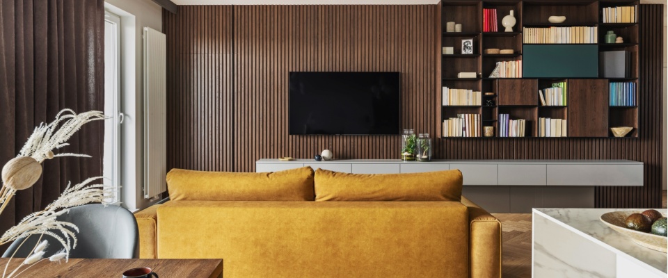 Modern living room with stylish decor, bookshelves, and a mounted TV, which are valuable items to protect and a reason why you need renters insurance.