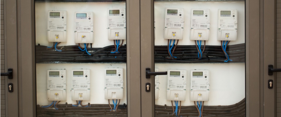 A row of modern smart electricity meters installed inside a secure glass cabinet.
