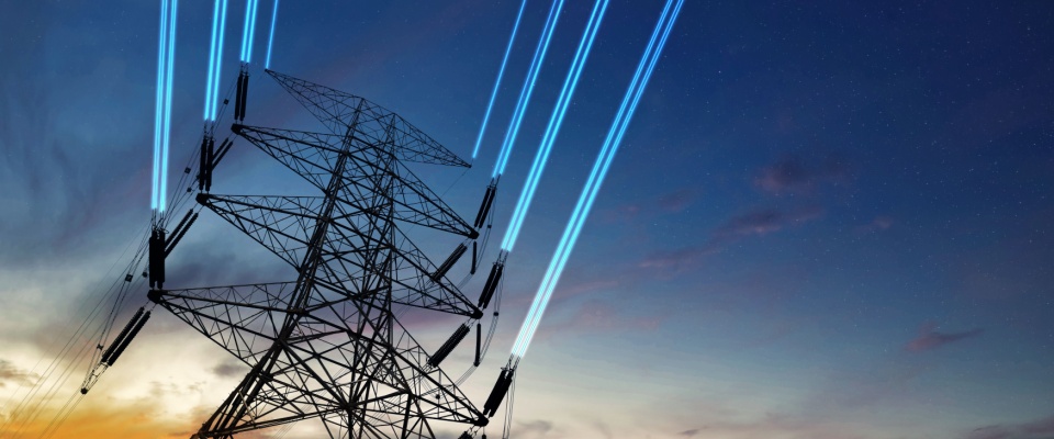 A towering power line stands against a twilight sky with glowing blue streaks representing energy flow, visually demonstrating how electricity works by transmitting electrical power over long distances.
