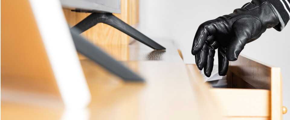 Gloved hand opening a drawer in a home, suggesting theft or burglary, visually stressing the importance of understanding the renters insurance effective date to ensure coverage is active in case of loss or damage.