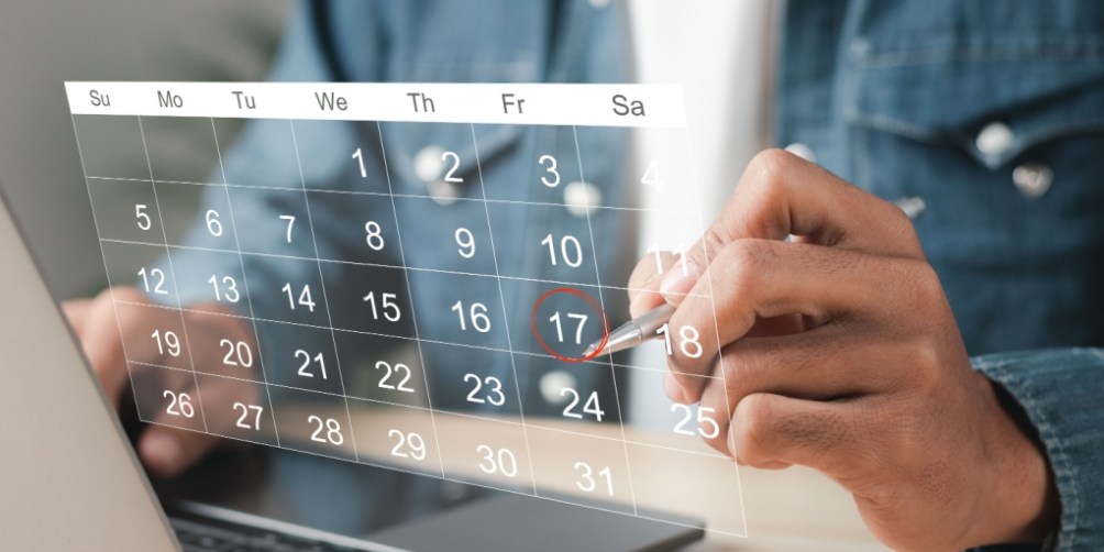 Person holding a pen and marking the effective date for their renters insurance policy on a transparent calendar overlay while working on a laptop.