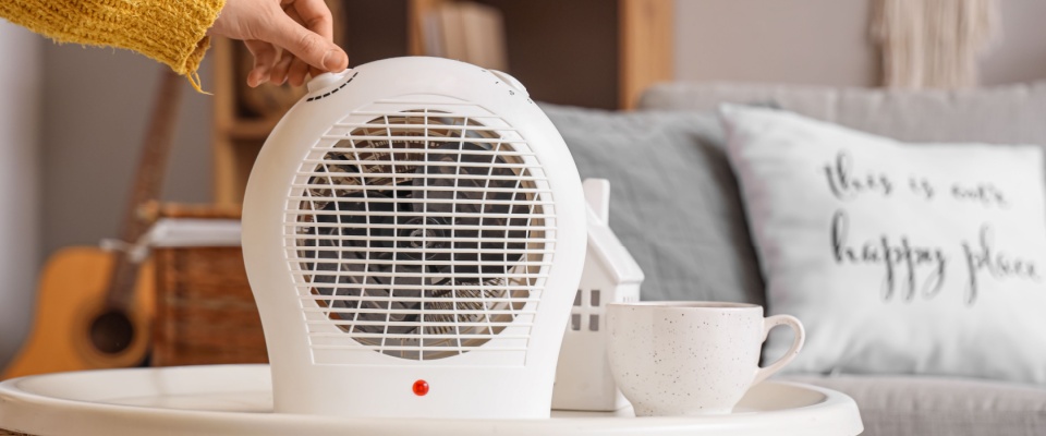 Person turning on a small space heater in a cozy living room, representing home maintenance and renters insurance coverage for appliance repairs.