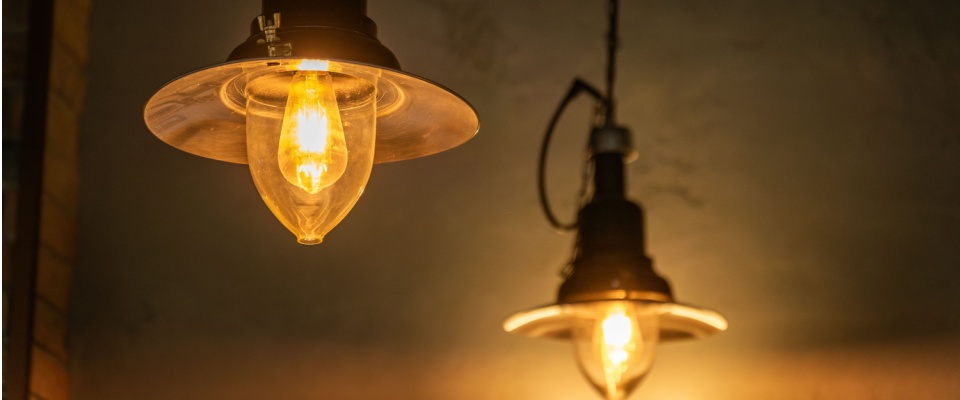 Warm glowing vintage light bulbs hanging from the ceiling, illustrating the historical impact and evolution following the invention of electricity.