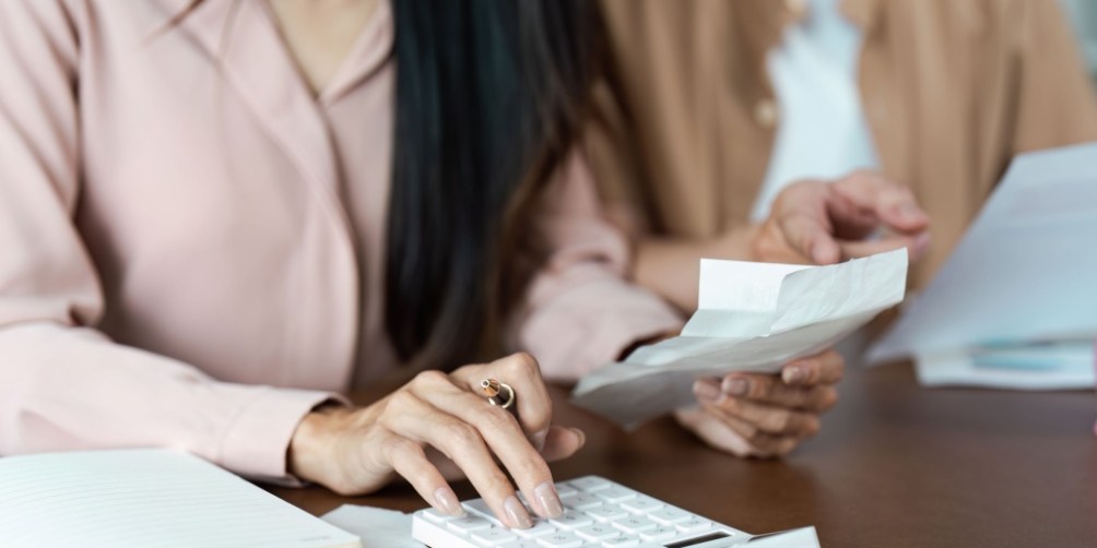Couple calculating household expenses and comparing electricity plans to find the most affordable energy option for their home.