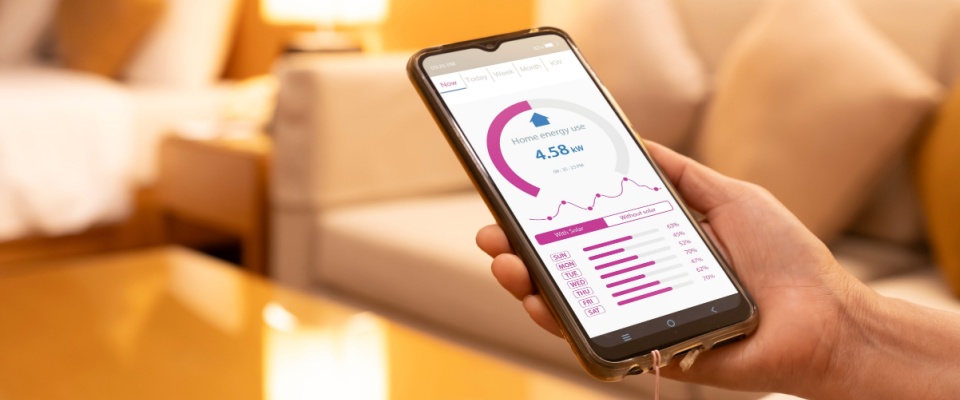 Smartphone displaying a home energy monitoring app with usage data, helping users track consumption and choose the right prepaid electricity plan.