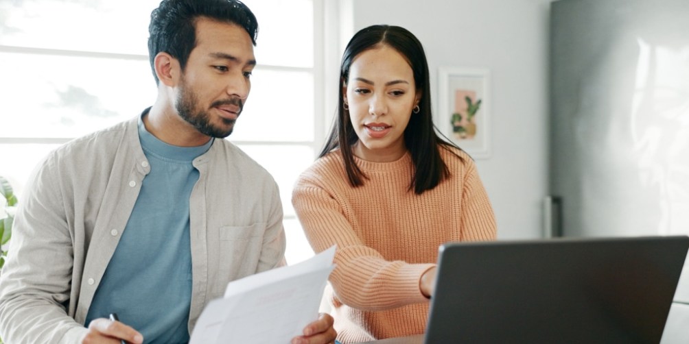 Couple reviewing rental documents on a laptop, researching how breaking a lease could hurt their credit score.