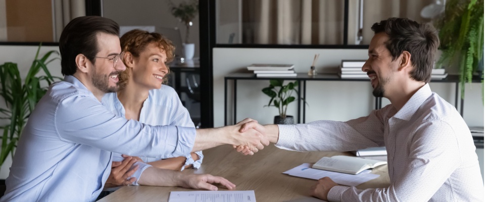 Couple discussing terms for breaking a lease with a landlord and shaking hands.