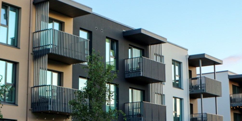 Row of modern residential buildings with balconies, representing housing options and structural coverage differences in homeowners versus renters insurance.