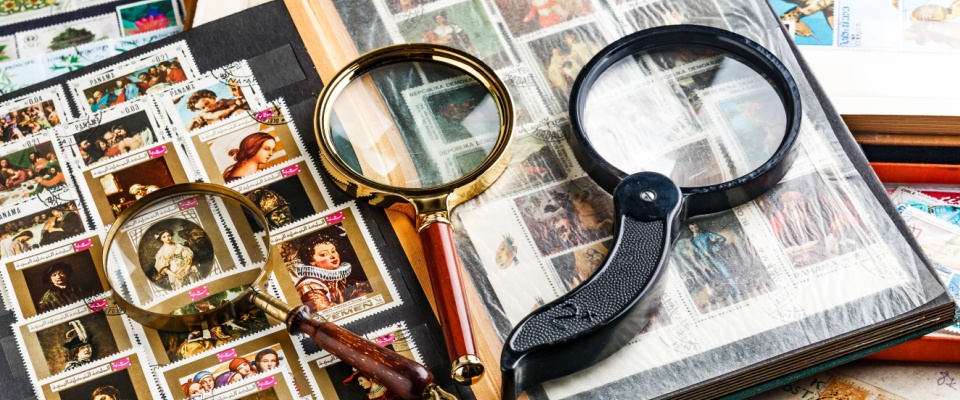 Close-up of an album with collectibles and magnifying glasses, illustrating why it’s important to compare renters insurance exclusions for valuable items.