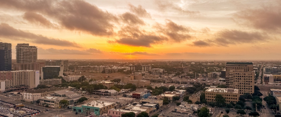 Aerial view of a Texas city skyline at sunset, representing how regional demand and market deregulation influence Texas electricity rates.