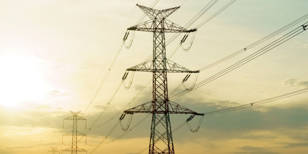High-voltage power lines stretching across the landscape, illustrating the energy grid infrastructure that impacts Texas electricity rates.