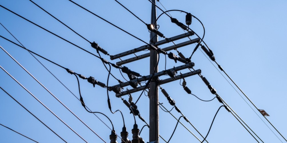 Utility power pole and transmission lines illustrating infrastructure costs that contribute to TDU delivery charges on electricity bills.