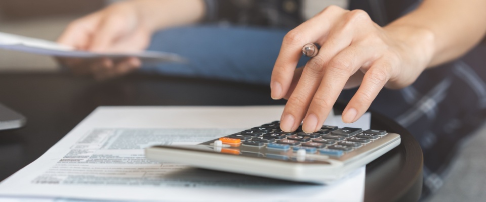 Person using a calculator and reviewing paperwork to determine whether renters insurance is tax deductible and how premiums may impact annual tax filings.